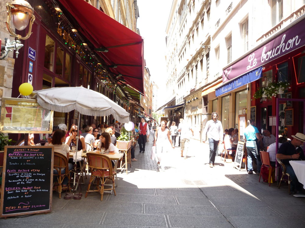 Sunny day in busy rue Merciere in Lyon with people shopping, sitting in cafes etc. 