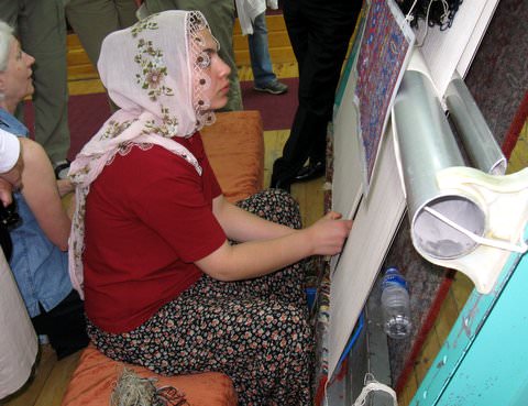 A woman at a carpet loom, hand-weaving