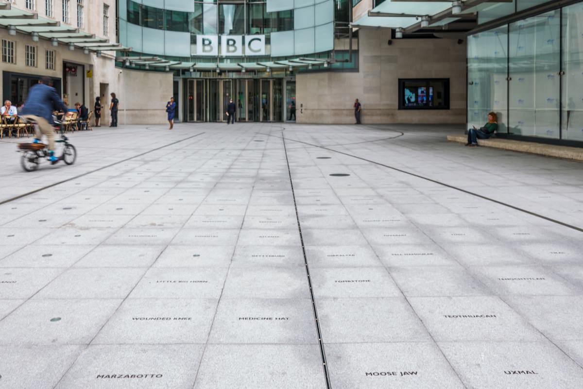 The entry courtyard to the BBC entrance. Small bronze plaques are inset into the concrete courtyard, memorializing places where atrocities and earth-shaking events have taken place in world history.