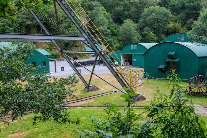 This picture shows the green buildings, ore carts, and gravel courtyard at the Dolaucothi gold mines.