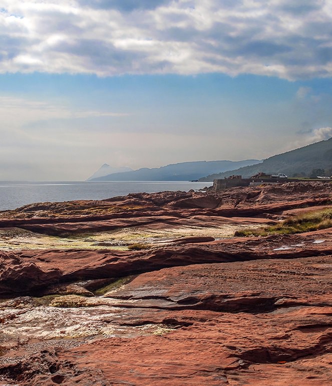 Arran’s red sandstone on the east coast has been quarried and used for castles, hotels, and cottages. In the far distance peeking above the mist is Holy Isle, a place of retreat.
