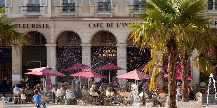 Central Square with water fountain and street cafe with red umbrellas, people enjoying a summer day at La Place du Marche in Ste. Germain en Laye