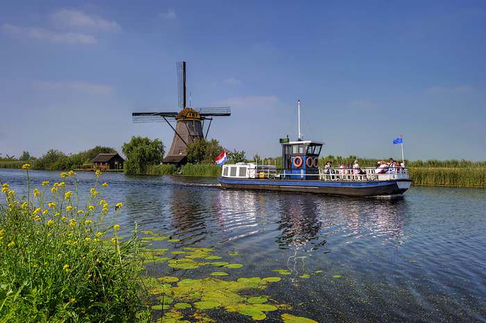 A tourist boat travels past the Kinderdijk windmills
