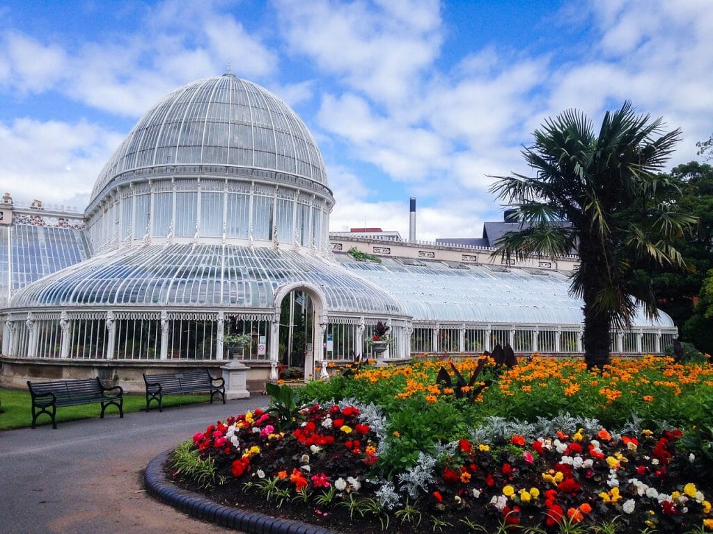 White Greenhouse in the Botanical Gardens in Belfast with colorful flowerbeds in front.