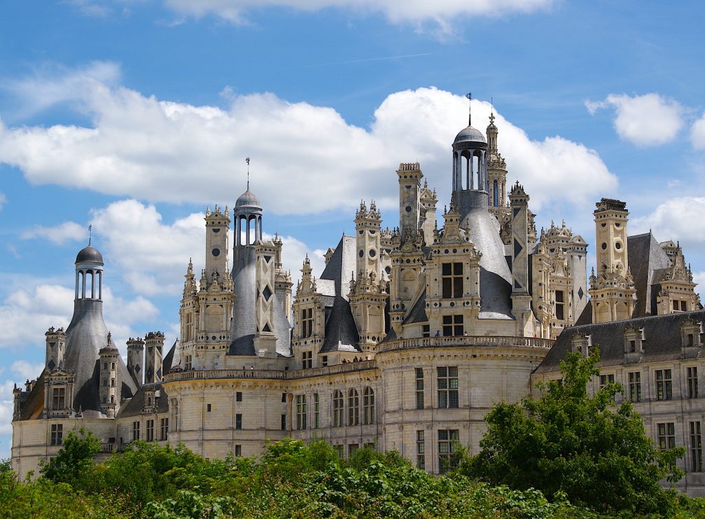 Beautiful french castle with many spires on sunny day with blue sky and stunning clouds