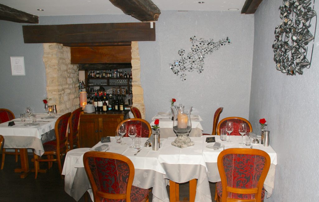 Cozy French Restaurant Interior - Tables with white table cloths, wood chairs, low ceiling with wood beams