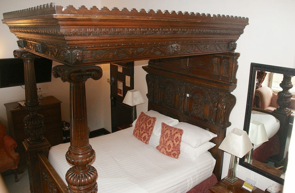 Lovely wood carved mahogany bed frame with a well made bed at Noel Arms hotel
