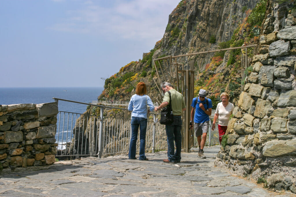 Entrance to Riomaggiore hiking trail in Cinque Terre - people walking on coastal hiking trail
