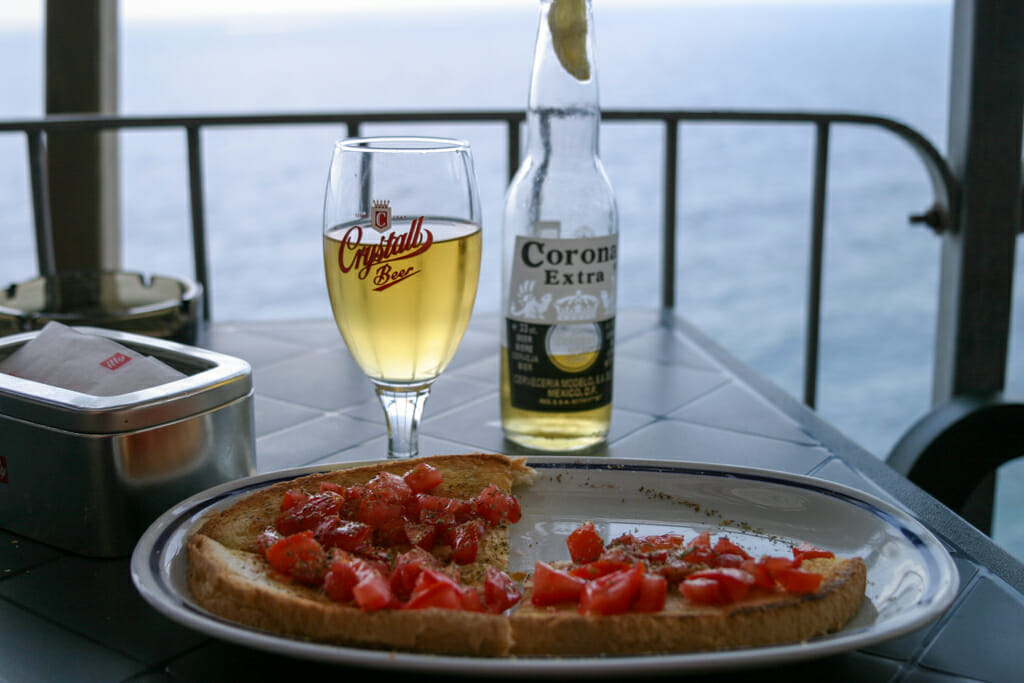 Bruscetta and beer on table overlooking the ocean