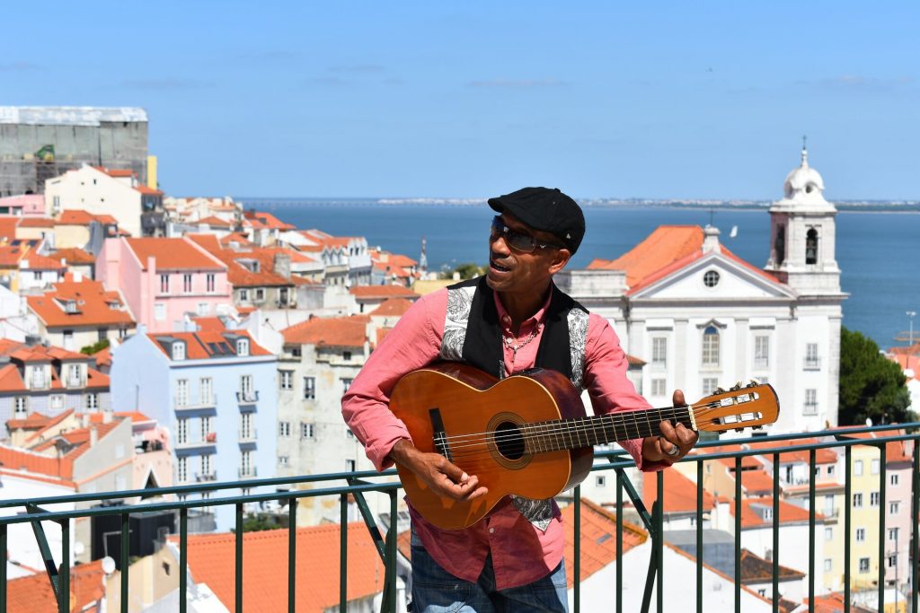 Guitar player singing with the town of Alfama at his back