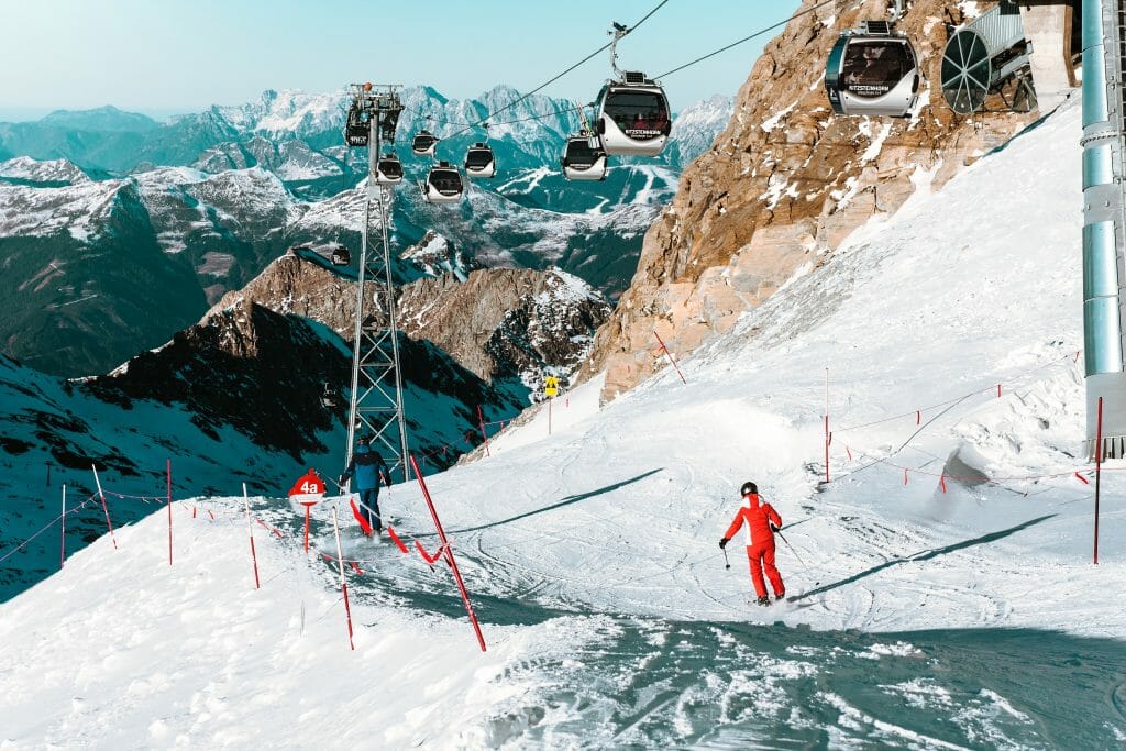 Person in red overall skiing under ski lift