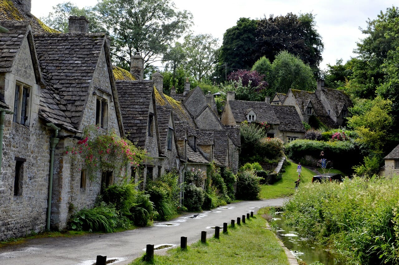picturesque stone houses along narrow street in the cotswolds, England