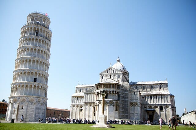 The Leaning Tower of Pisa next to a cathedral with hoards of tourists waiting to snap pictures