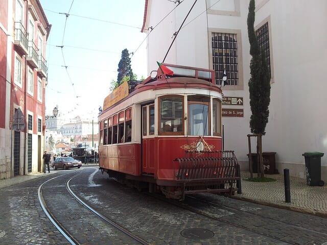 The tram traveling up a quiet street with the activity of the town a distance behind it