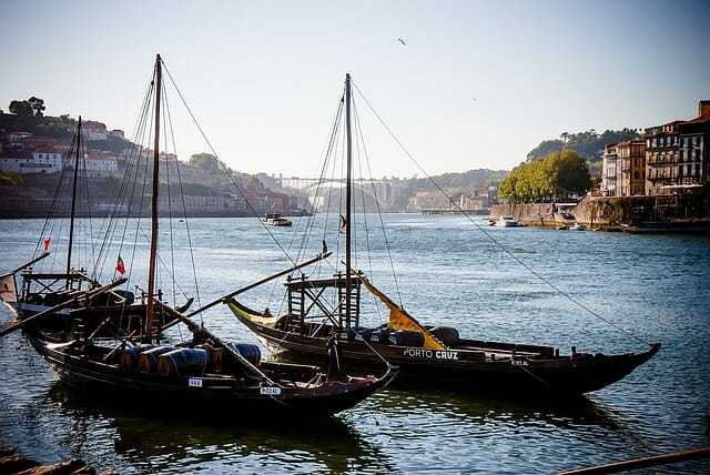 Small boats floating on the River Douro with the bridge in the distance