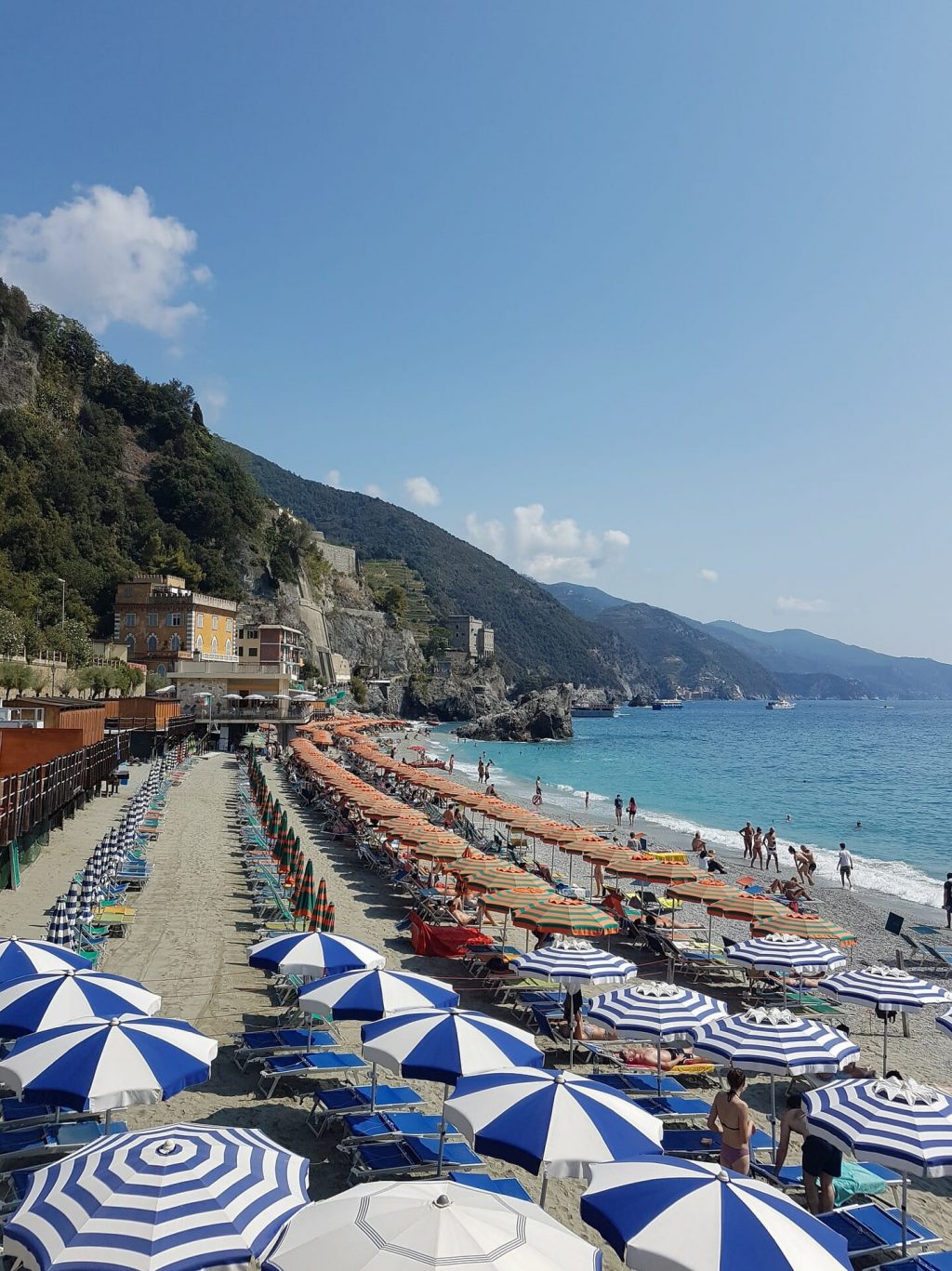 Clusters of colorful beach umbrellas shading visitors and Monterosso locals