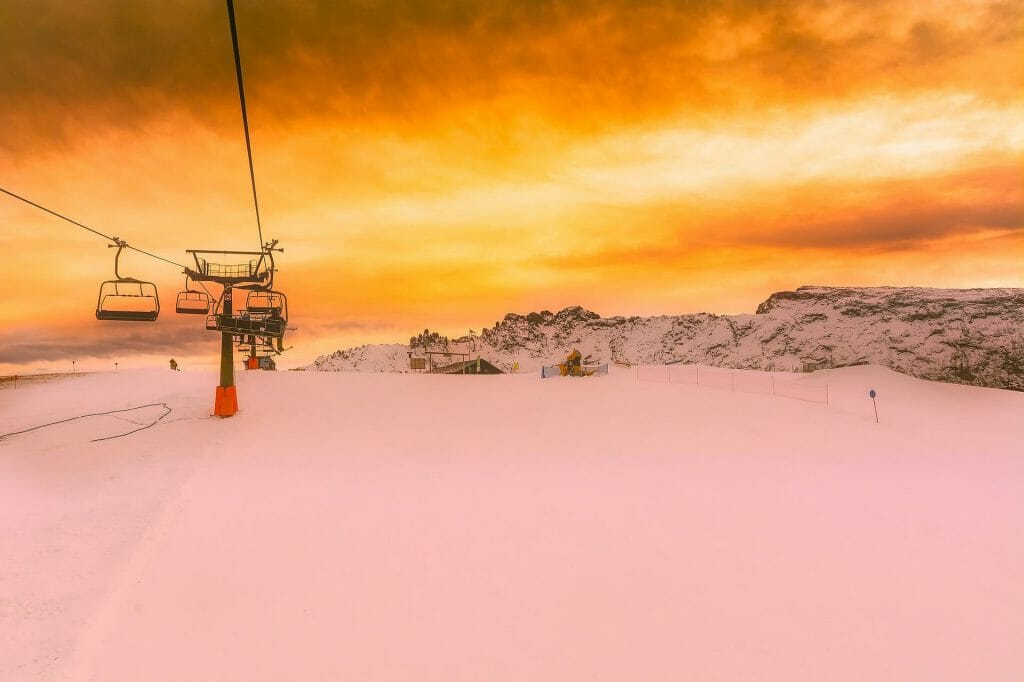 Sunsetting on the snowy Italian ski slopes, the chair lifts hanging over head