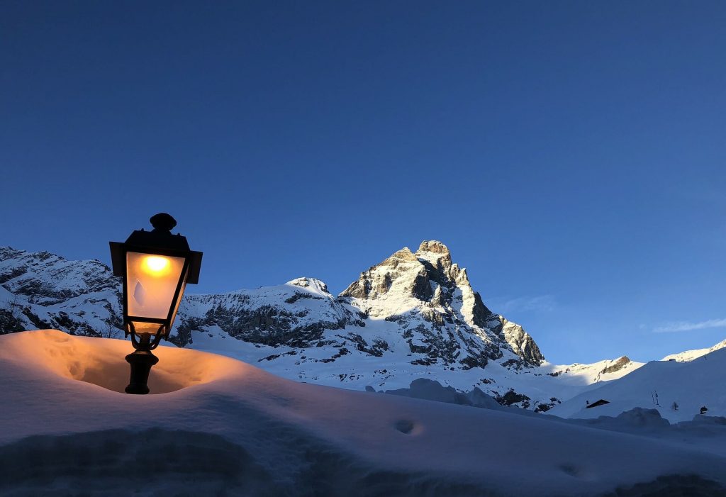 A street lamp illuminating the high snow with Mount Matterhorn in the back