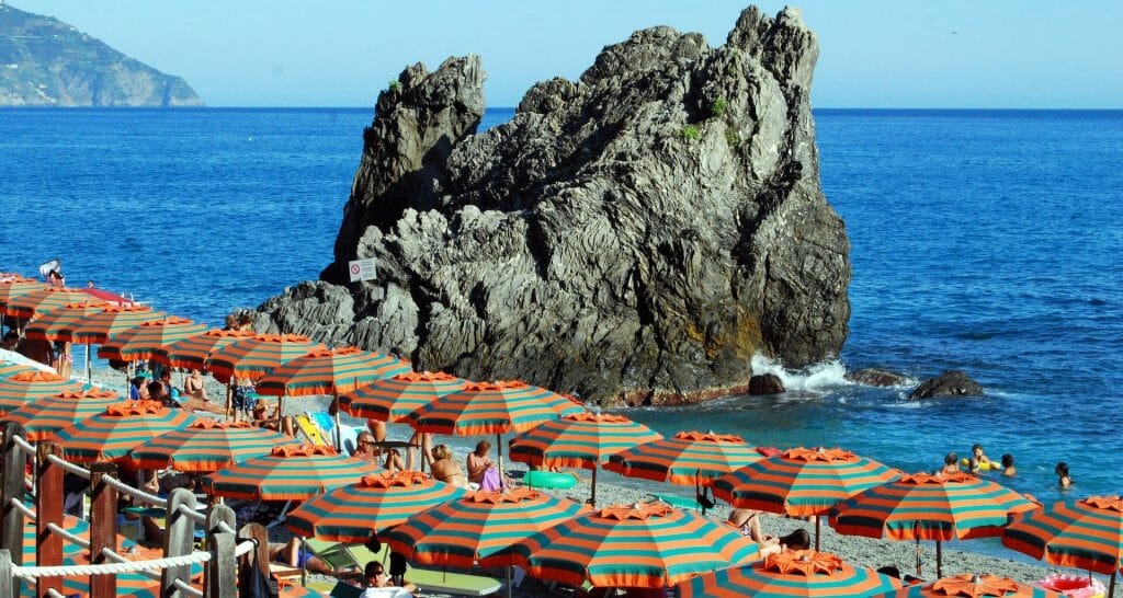 Sea boulder in the background of a sea of orange and green beach umbrellas