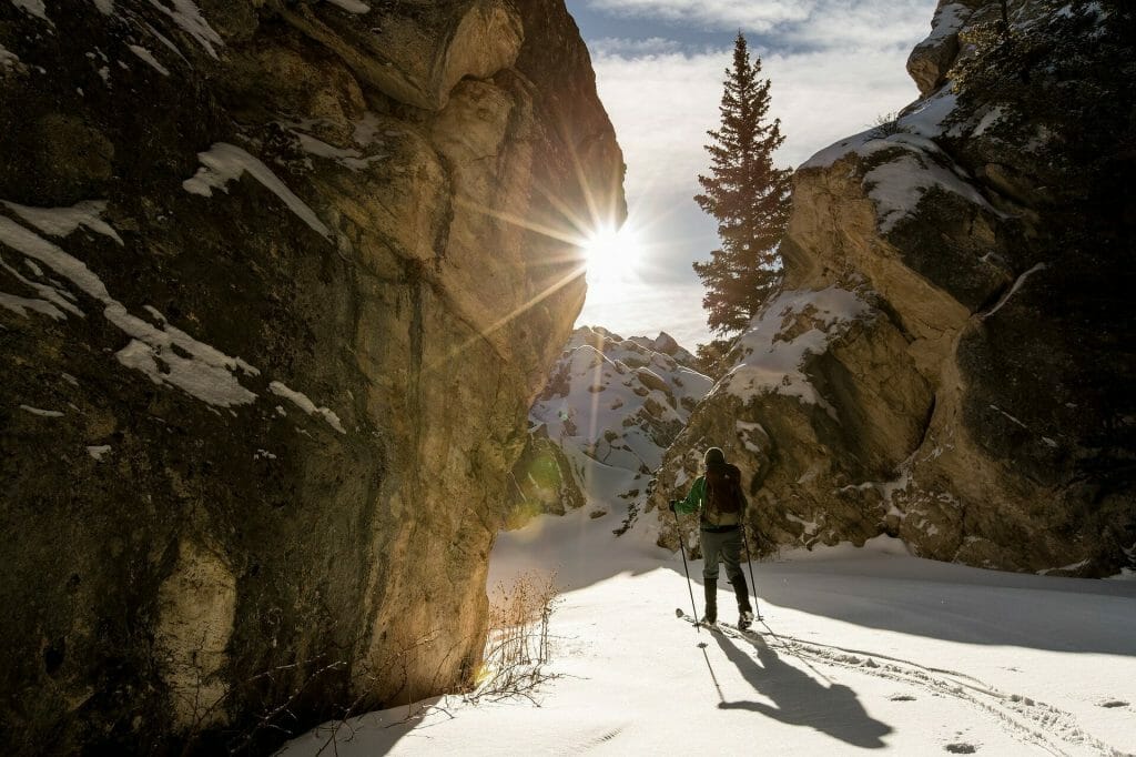 Person cross country skiing between towering cliffs