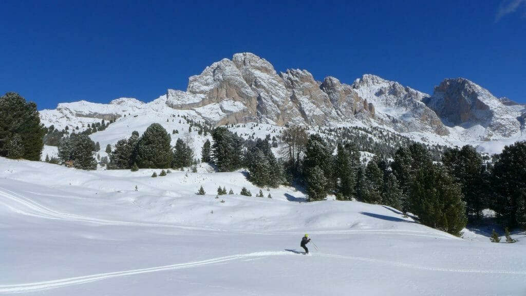 Person skiing the Dolomite slopes on a sunny day with more mountains in the distance