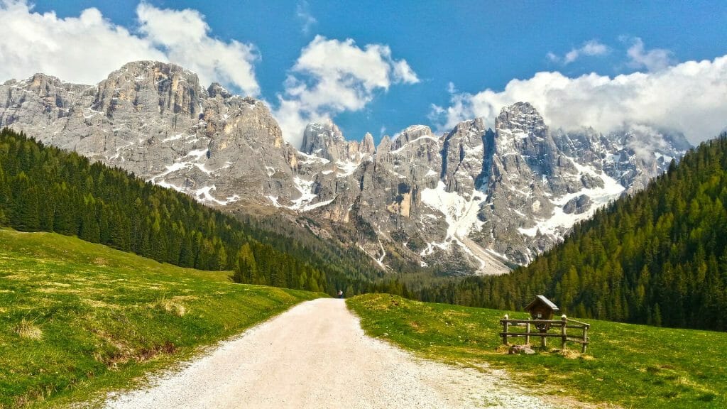 Sunny day on a trail with the snowy Dolomites in the background