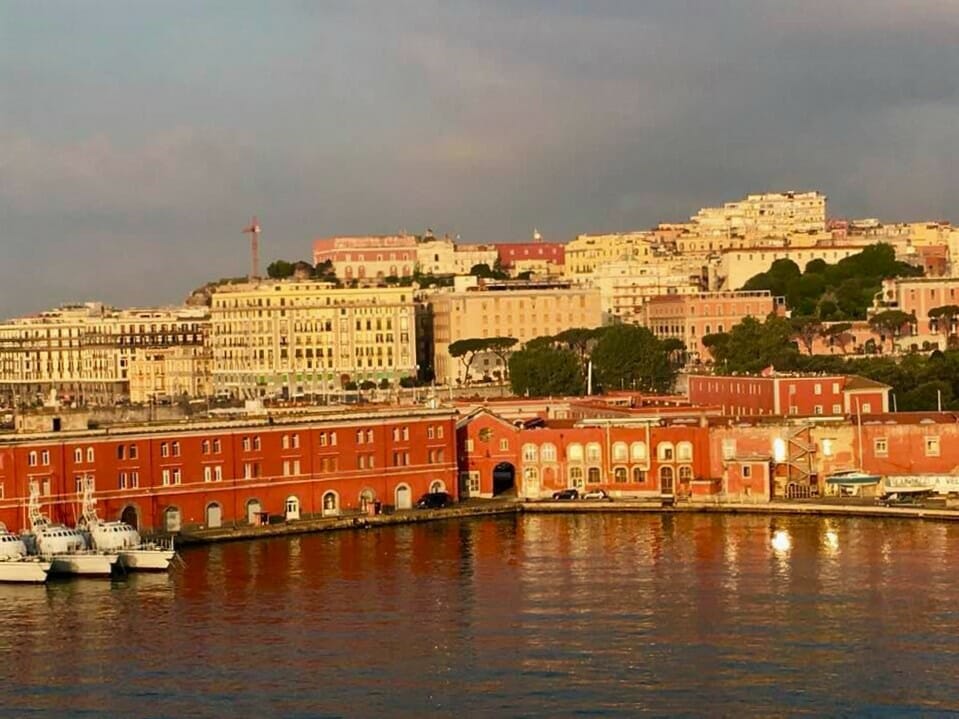 Coastal view of Naples, Italy with the warm colored buildings gracing the shores near the bay as the sun rises