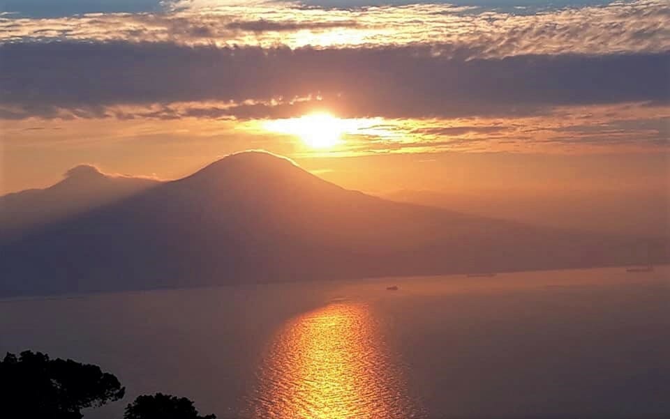 Sun setting over Mt. Vesuvius while the water reflects the light back gracefully