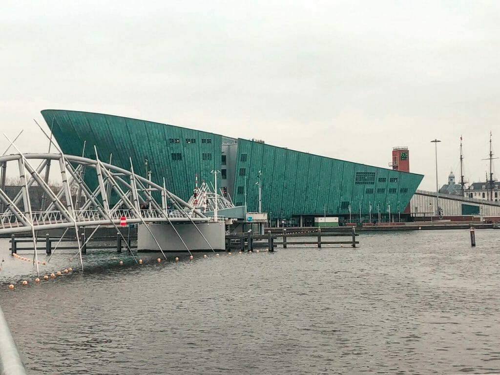 Bridge coming over the water to the turquoise NEMO museum on a gloomy day