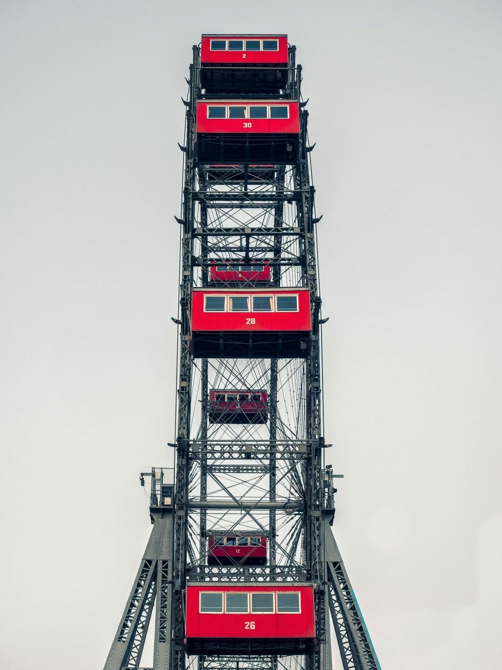 Side view of the Vienna ferris wheel with vibrant red cars on a gray day