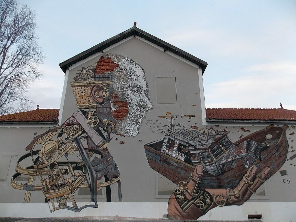 Mural of a man blowing on a broken boat in the streets of Lisbon