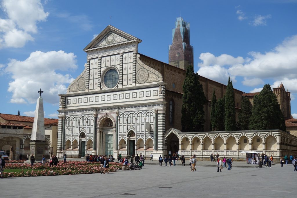 On a sunny day in Florence, visitors file in and out of the Santa Maria Novella with it's sleek black and white architecture