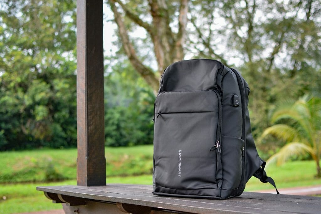 Black backpack sitting on a picnic table at the park during the day