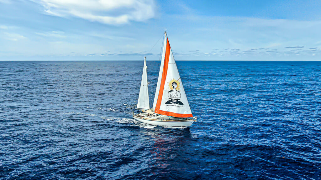 SV Delos sail boat with white/orange sails with buddha image in the middle of the Atlantic. 