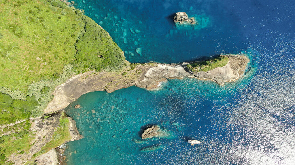 Aerial shot of turquoise water with rugged coastline and cliffs in Azores Islands