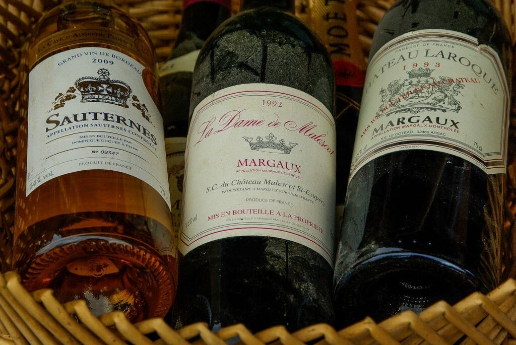 Basket of three Bordeaux wine that are slightly dusty and ages