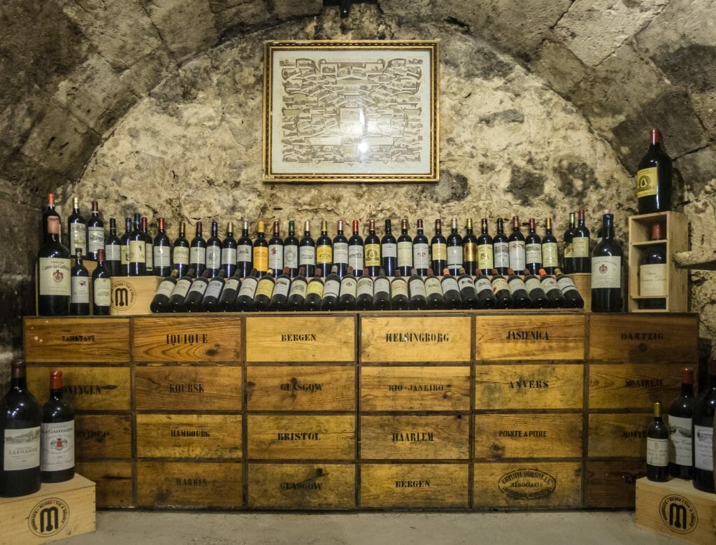 Wood boxes stacked in a vaulted cellar with Burgundy wine bottles on on top