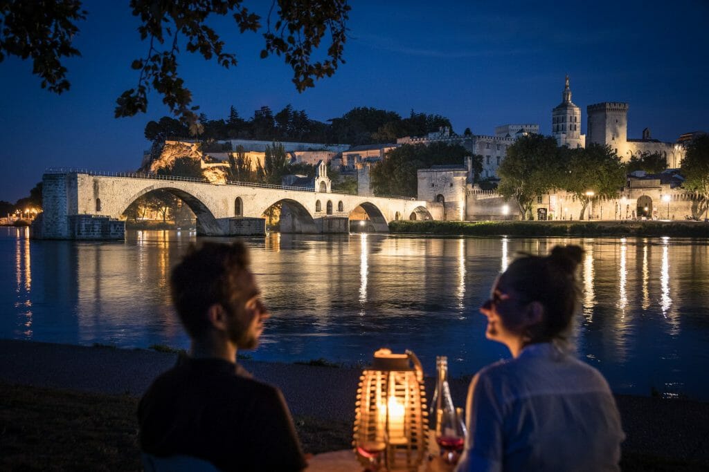 Couple on table with candle light in front of Pont Saint-Bénézet Bridge in Avignon