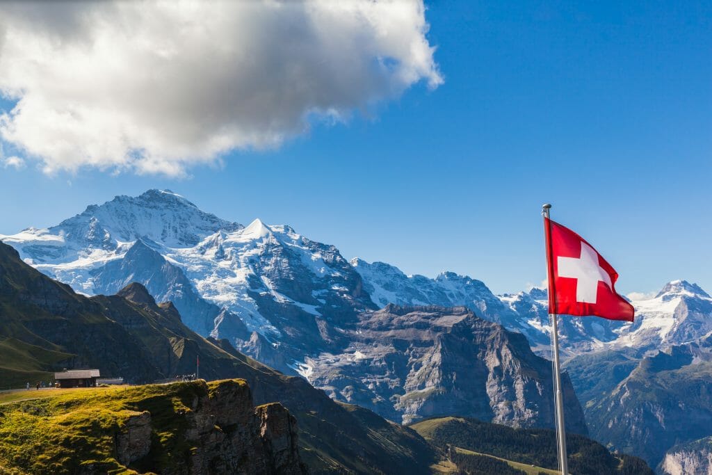 Alpine Panorama with Swiss flag (red flag with white cross) in the foreground