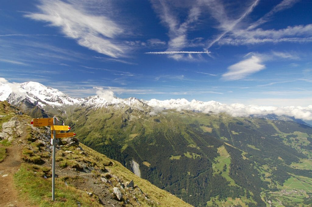 Yellow trail signs on a hiking trail in switzerland overlooking the Swiss alps