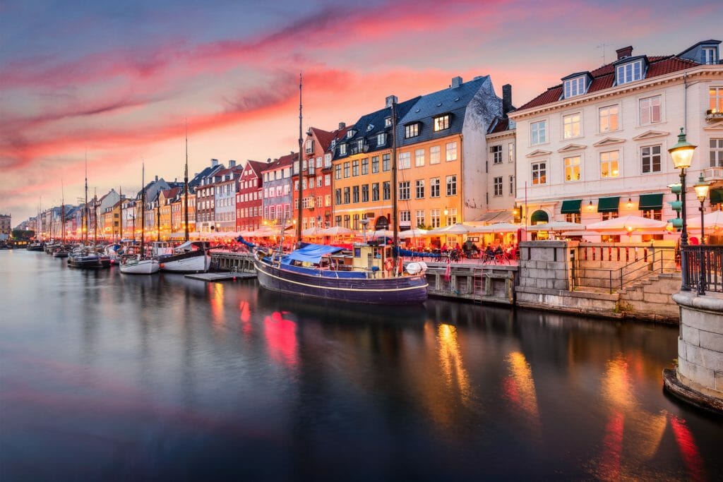 Copenhagen, Denmark on the Nyhavn Canal at sunset with colorful pink and purple sky