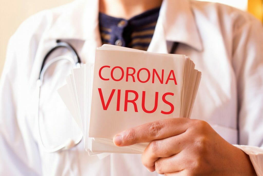Doctor in white lab coat holding cards with Corona Virus printed on them