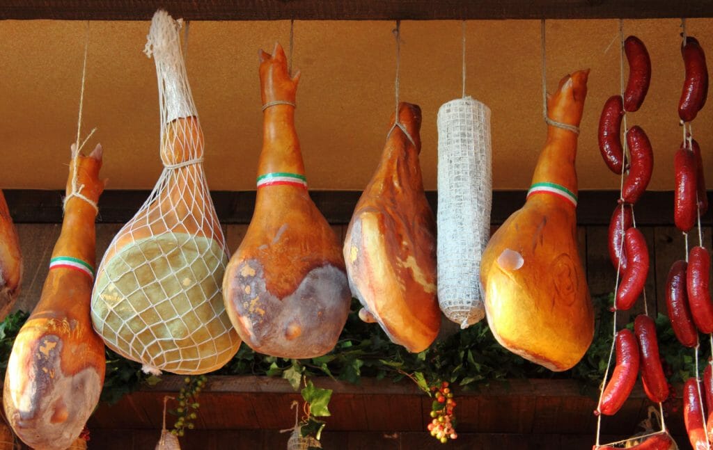 Emilia Romagna Food - Parma Ham hanging in a delicatessen shop in Italy