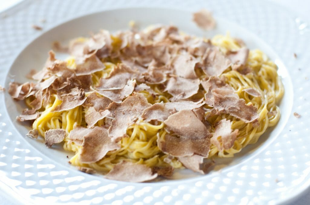 Yellow Tajarin pasta with butter and truffle on a white plate