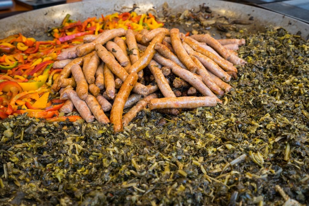 Typical dish of Puglia with sausage, turnip top and peppers, prepared in a large pot during a food fair