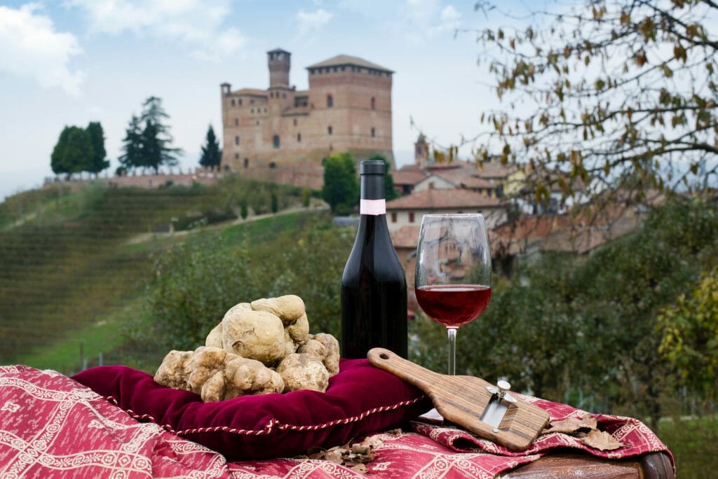 Still Life of White Truffles from Piedmont, truffles cuts and bottle with glass of red wine, with a view of the vineyards and the castle of Grinzane Cavour