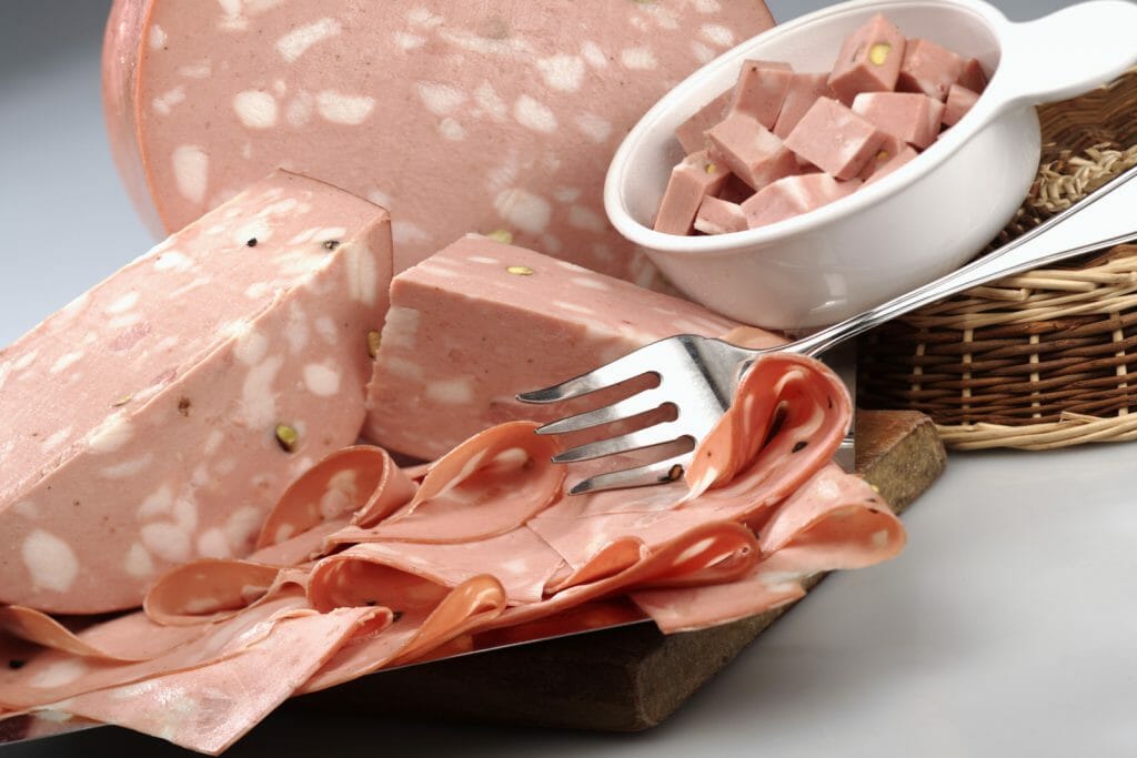 Whole, sliced and diced Mortadella arranged on a plate with fork
