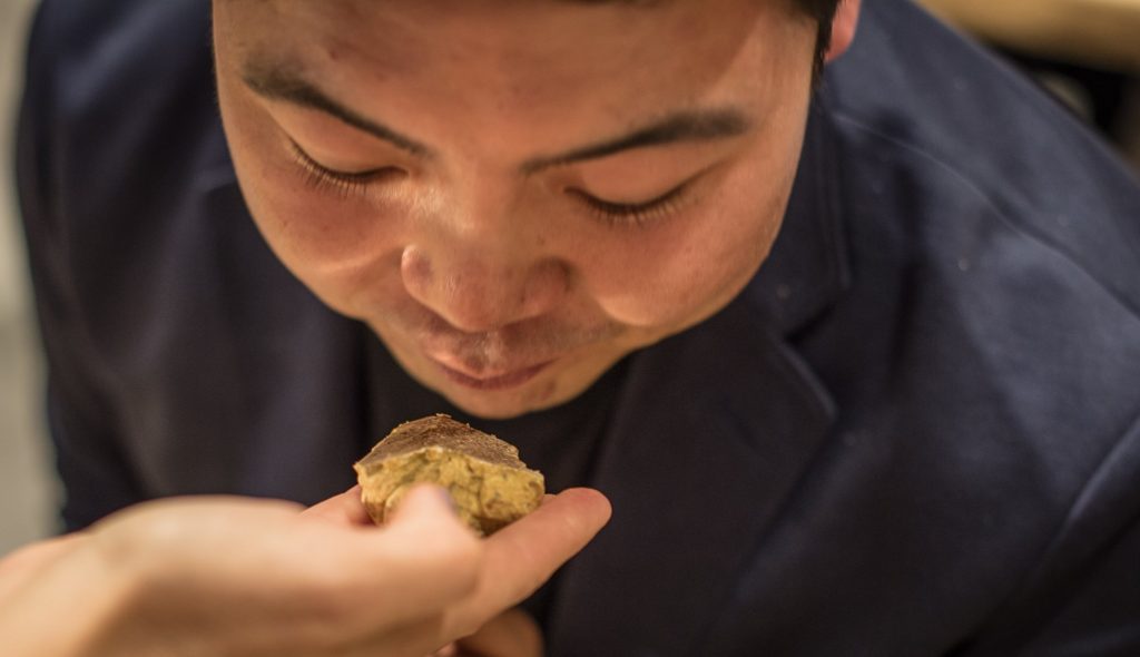 closeup of man sniffing white truffle on someons hand