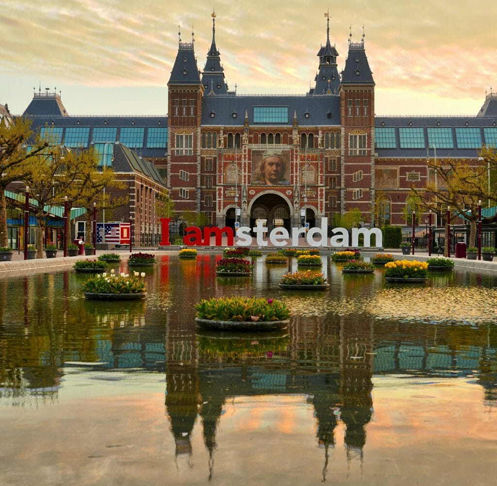 AMSTERDAM, NETHERLANDS: Frontal view of the Rijksmuseum (State Museum) with billboard of Rembrandt with its pond reflection at sunrise in Amsterdam, Holland