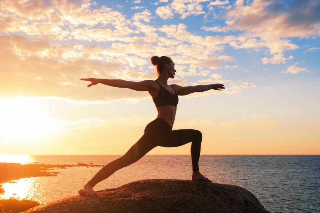 caucasian fitness woman practicing yoga at sunset